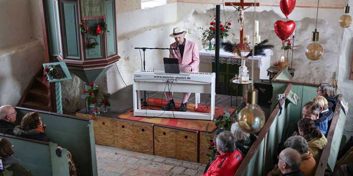 Thomas Kübler beim Valentinskonzert in der Dorfkirche Ipse am 14. Februar 2026: Der Chansonnier sitzt am Klavier auf einem Podest im Altarraum, davor verfolgt das Publikum das ausverkaufte Konzert des Vereins Ipse Excitare.