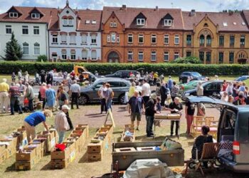 Flohmarkt auf dem Harbig-Sportplatz in Gardelegen: Viele Besucher stöbern bei sommerlichem Wetter an Trödelständen mit Büchern, Kleidung und Gebrauchtwaren – im Hintergrund die Gründerzeitfassaden der Schillerstraße.